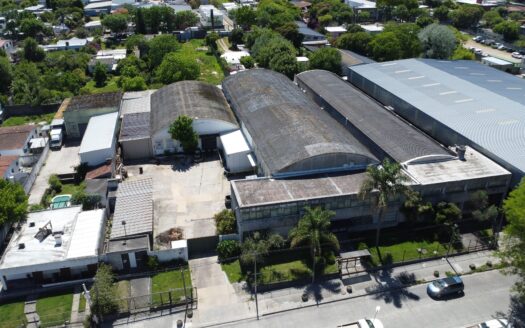Vista aérea de un amplio complejo de nave industrial y depósito logístico con generosa explanada frontal de maniobras, ubicado en una zona estratégica de Montevideo con excelentes accesos